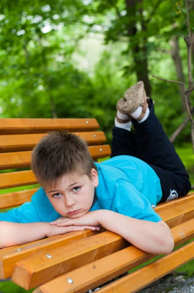 De jongen lag op een bank — Stockfoto