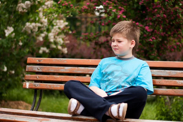 Trauriger Junge sitzt auf einer Bank — Stockfoto