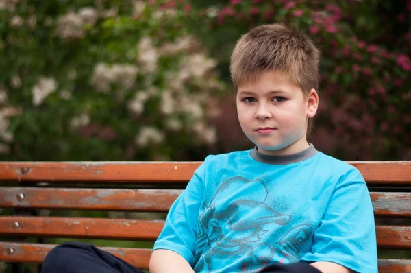Smutny chłopiec siedzi na ławce — Zdjęcie stockowe