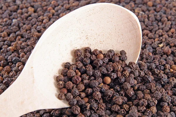 Black pepper on wooden spoon — Stock Photo, Image