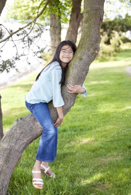 Young girl resting on a tree branch clipart