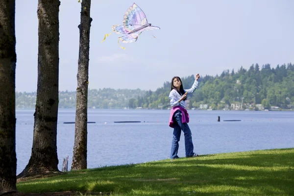 Biracial asiatisk tjej flyga drake vid sjön — Stockfoto