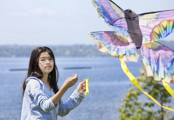 Biracial asiático menina voando pipa pelo lago — Fotografia de Stock