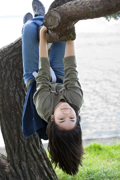 Young teen girl hanging upside down on tree limb — Stock Photo, Image
