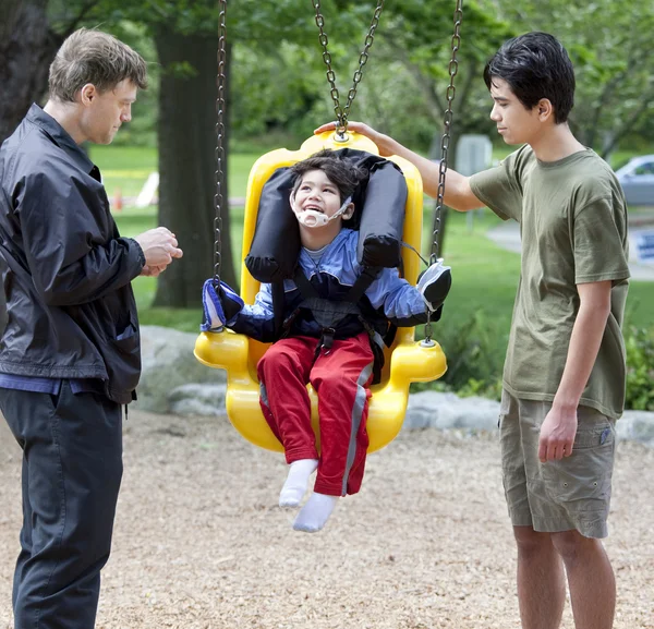 Disabled little boy swinging on special needs swing — Stock Photo, Image