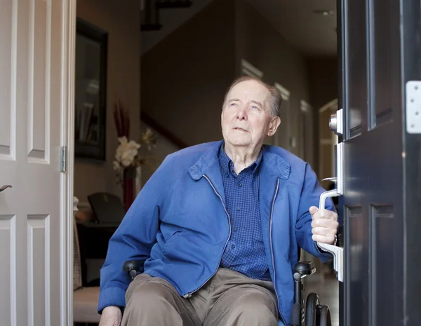 Homme âgé en fauteuil roulant à sa porte d'entrée, levant les yeux — Photo