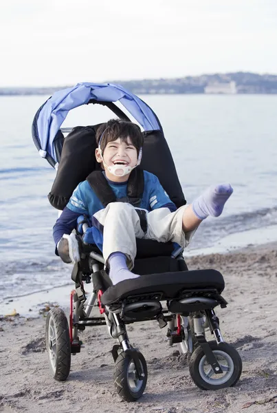 stock image Happy disabled boy in wheelchair on the beach