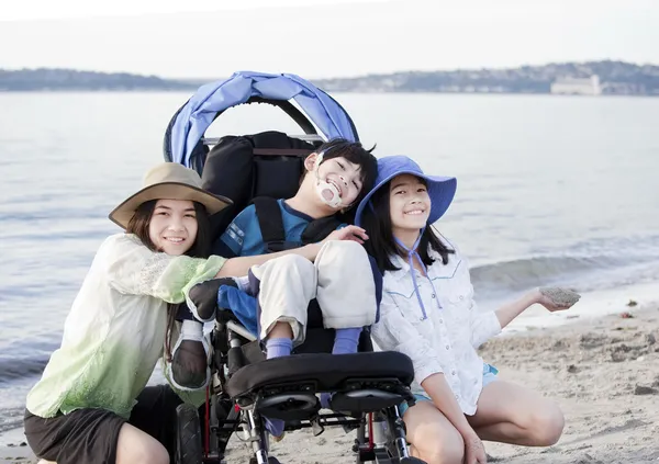 Systrarna tar hand om funktionshindrade bror på stranden — Stockfoto