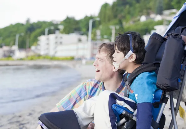 Padre disfrutando de la playa con hijo discapacitado —  Fotos de Stock