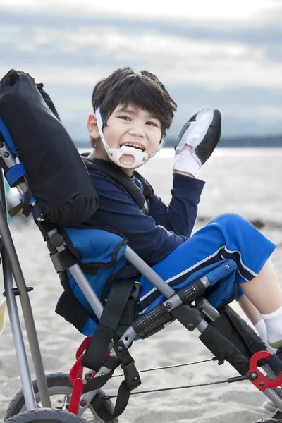 Glücklicher behinderter fünfjähriger Junge im Rollstuhl am Strand — Stockfoto