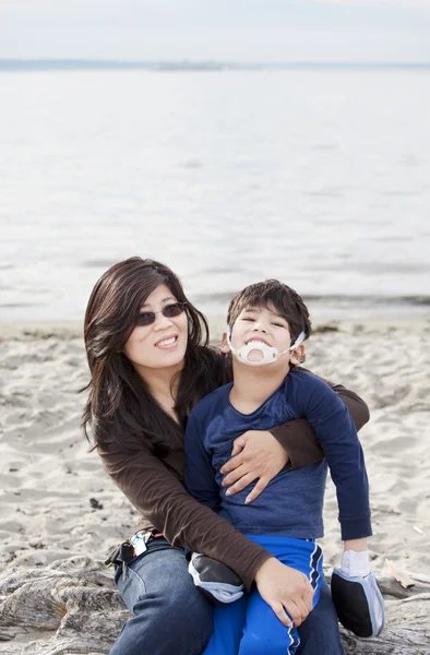 Mère tenant son fils handicapé sur la plage — Photo