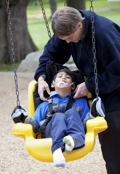 Vater drückt behinderten Sohn auf Handicap-Schaukel — Stockfoto