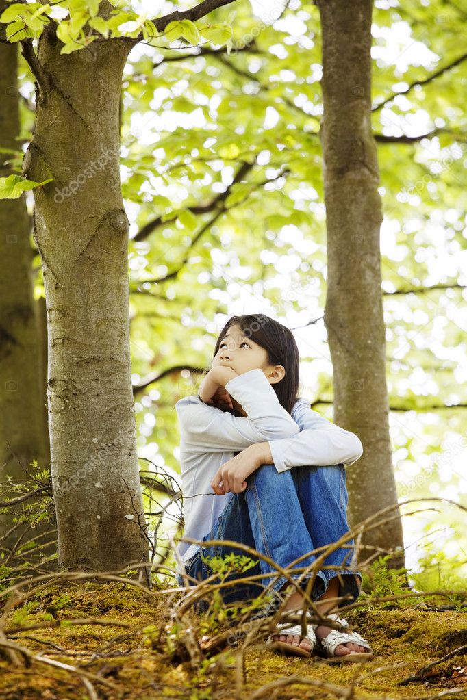 Ten year old girl sitting quietly in woods