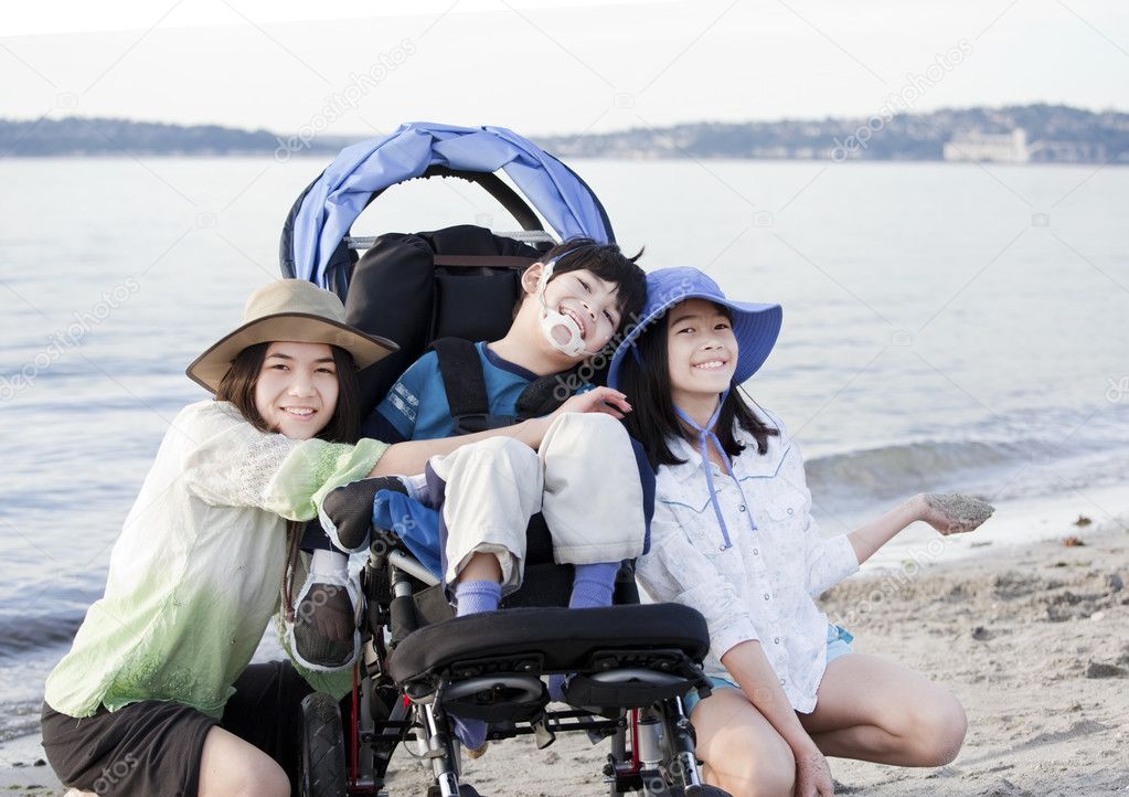 Sisters taking care of disabled brother on beach