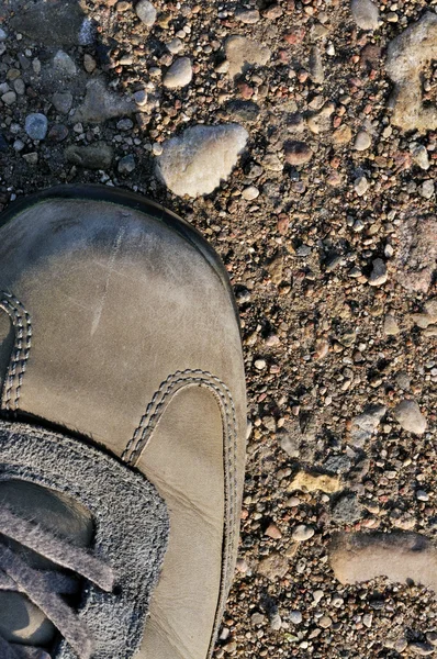 Hiking boot off-road shoe on hard arid dried soil in sepia, vert — Stock Photo, Image