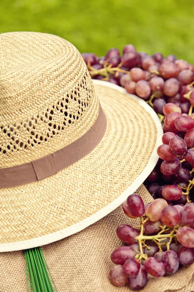 Straw hat and red grapes — Stock Photo, Image