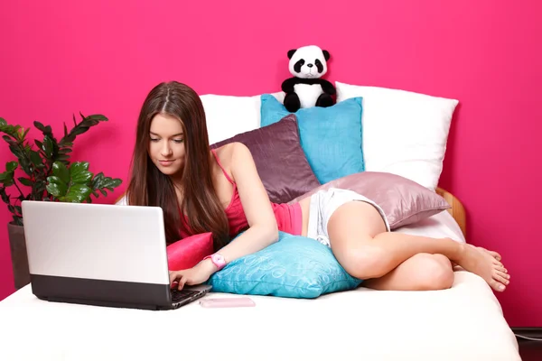 Adolescente morena usando um laptop em seu quarto — Fotografia de Stock