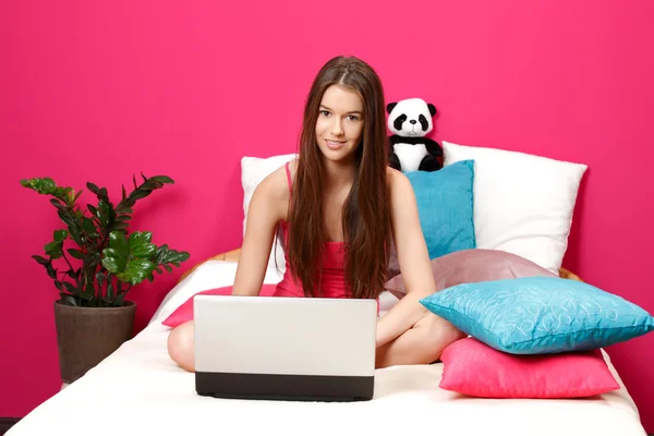 漂亮的黑发少年坐在她的房间和使用的便携式计算机 — 图库照片