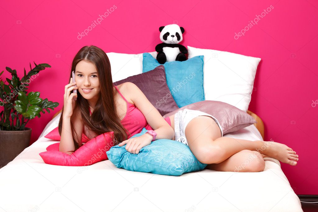 Beautiful teenager making a call in her pink room