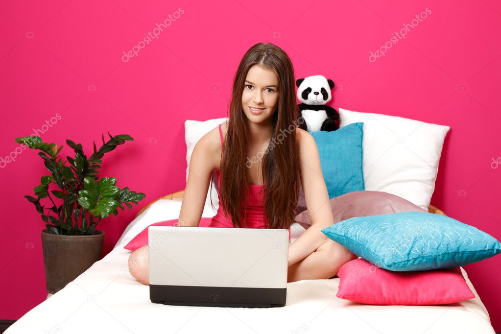 Nice brunette teenager sitting in her room and using laptop