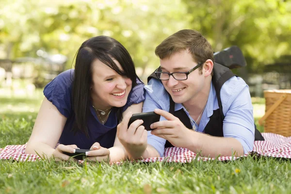 Junges Paar beim gemeinsamen SMS-Schreiben im Park — Stockfoto