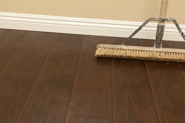 Push Broom on a Newly Installed Laminate Floor and Baseboard — Stock Photo, Image