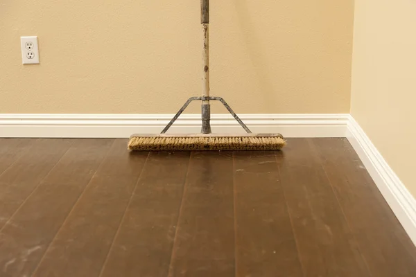 Spingere Scopa su un nuovo pavimento in laminato installato e battiscopa — Foto Stock