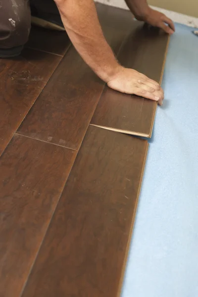 Людина встановлює нові ламіновані дерев'яні підлоги — стокове фото