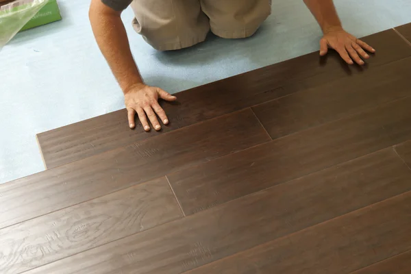 Homem instalando novo piso de madeira estratificada — Fotografia de Stock