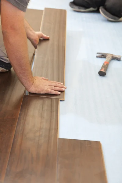 Человек закладывает новое ламинированное деревянное половое покрытие — стоковое фото