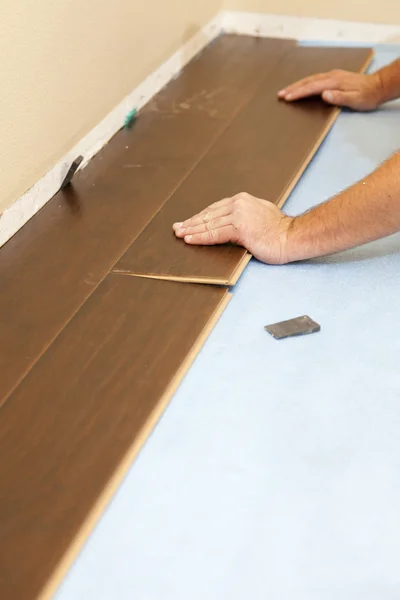 Людина встановлює нові ламіновані дерев'яні підлоги — стокове фото