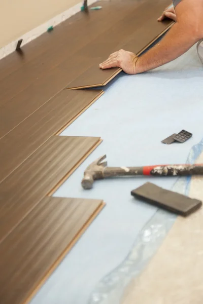 Человек закладывает новое ламинированное деревянное половое покрытие — стоковое фото