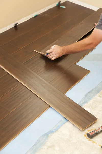 Homem instalando novo piso de madeira estratificada — Fotografia de Stock