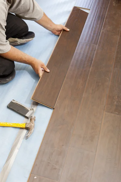 Uomo Installazione di nuovi pavimenti in legno laminato — Foto Stock