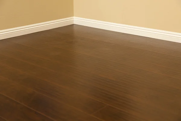 Pavimenti in laminato marrone di nuova installazione e battiscopa in casa — Foto Stock