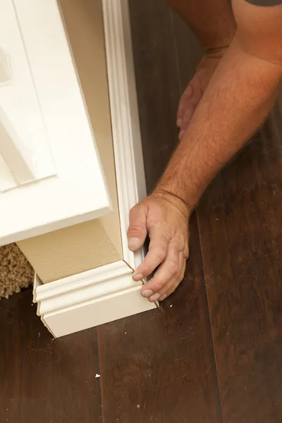Contractor Fitting New Baseboard to Wall and New Laminate Floori — Stock Photo, Image