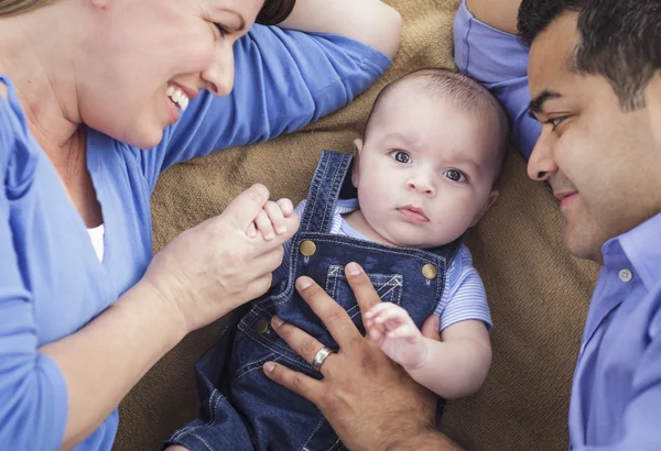 Famille mixte avec un bébé garçon jouant sur la couverture — Photo