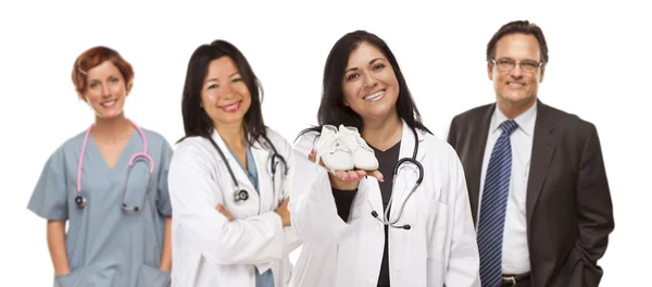 Hispanic Female Doctor or Nurse with Baby Shoes and Support Staf — Stock Photo, Image
