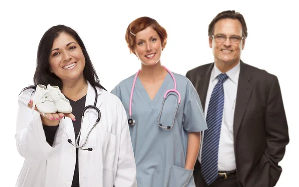Hispanic Female Doctor or Nurse with Baby Shoes and Support Staf Stock Picture