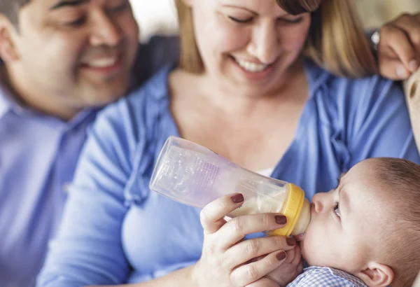 Felice razza mista coppia bottiglia alimentando il loro figlio — Foto Stock