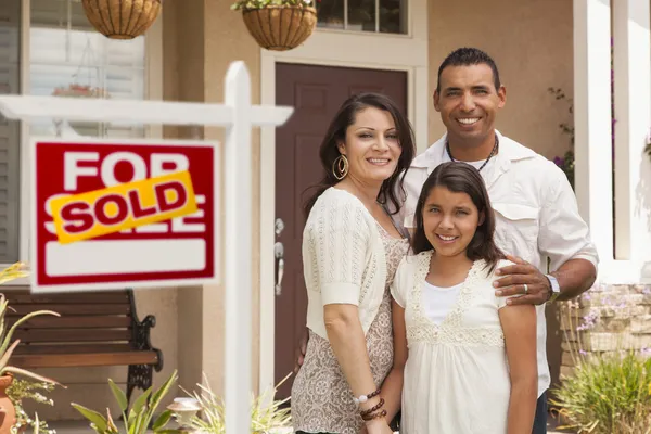 Familia hispana frente a su nuevo hogar con letrero vendido — Foto de Stock