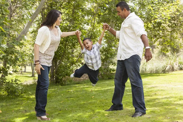 Испанская мать и отец свингуют сына в парке — стоковое фото