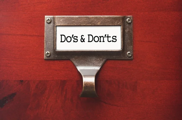 Яскравий дерев'яний кабінет з файловою етикеткою Do's та Don'tts — стокове фото
