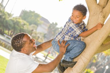 Happy Mixed Race Father Helping Son Climb a Tree clipart