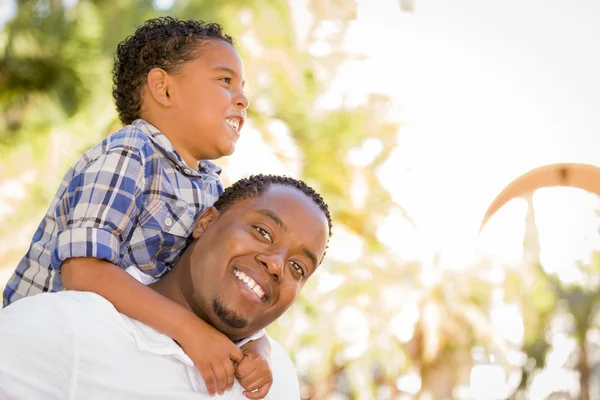 Mieszanej rasy ojciec i syn gra piggyback — Zdjęcie stockowe
