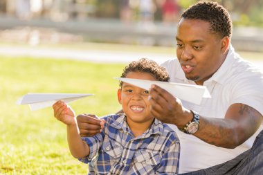 Mixed Race Father and Son Playing with Paper Airplanes clipart