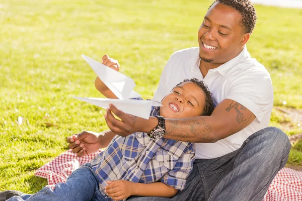 Отец и сын смешанной расы играют с бумажными самолетами — стоковое фото