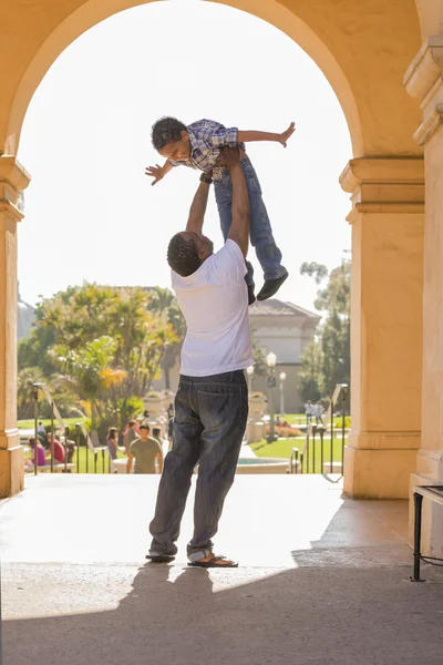 Afro-americano pai levantando misto raça filho no o parque — Fotografia de Stock