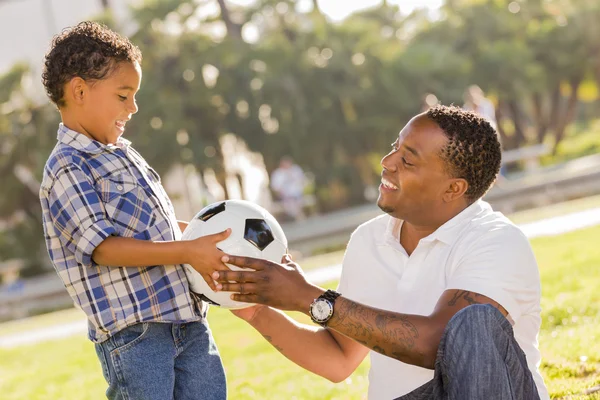 Padre manos nueva pelota de fútbol para el hijo de raza mixta — Foto de Stock