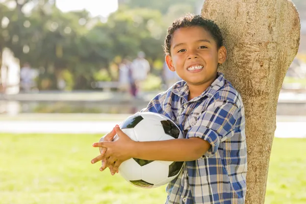 Chlapec smíšené rasy s fotbalovým míčem v parku — Stock fotografie